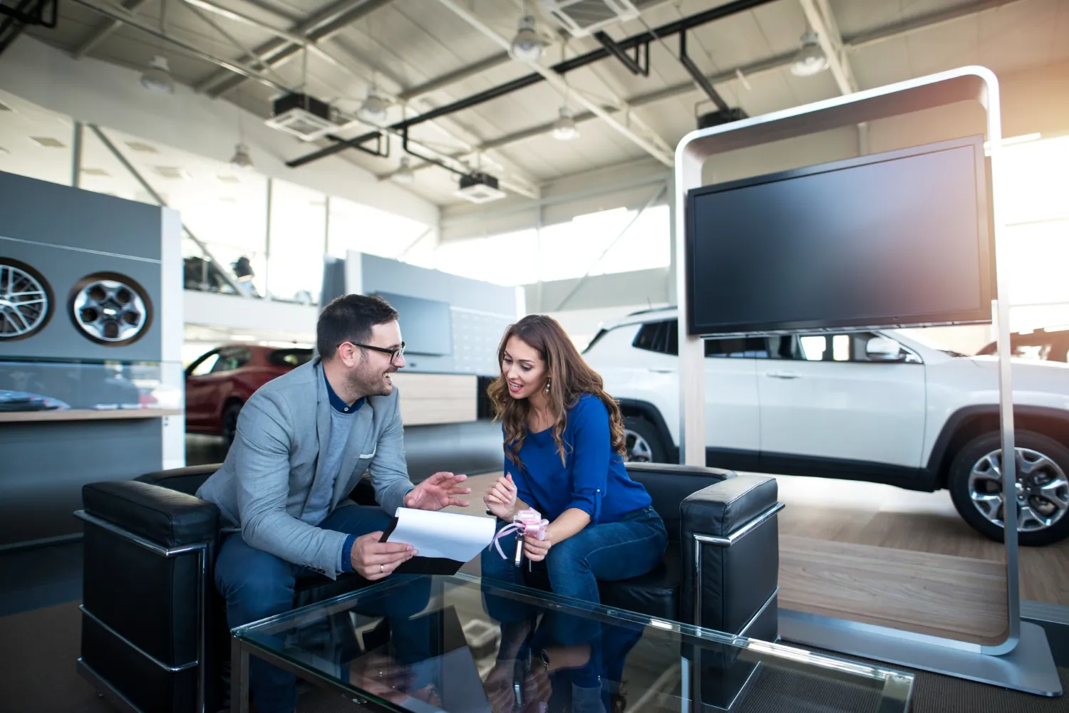 A salesperson showing a customer a vehicle in a dealership showroom